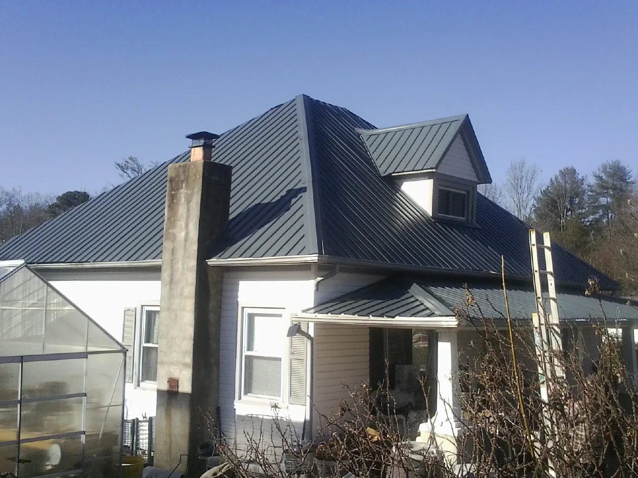 Dark blue standing seam metal roof on a white farmhouse with dormer — Slate & Tile Roof Repair by Roofing Brothers in Ashley Falls