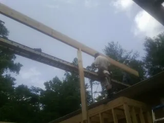 Carpenter setting a ridge beam over a new addition frame — Ice Dam Removal by Roofing Brothers in Ashley Falls