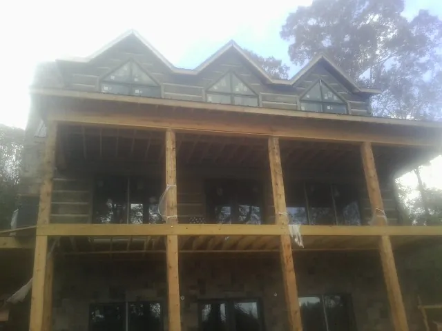 Dormers and porch framing on a large log home under construction — Roof Coating work by our crew in Ashley Falls