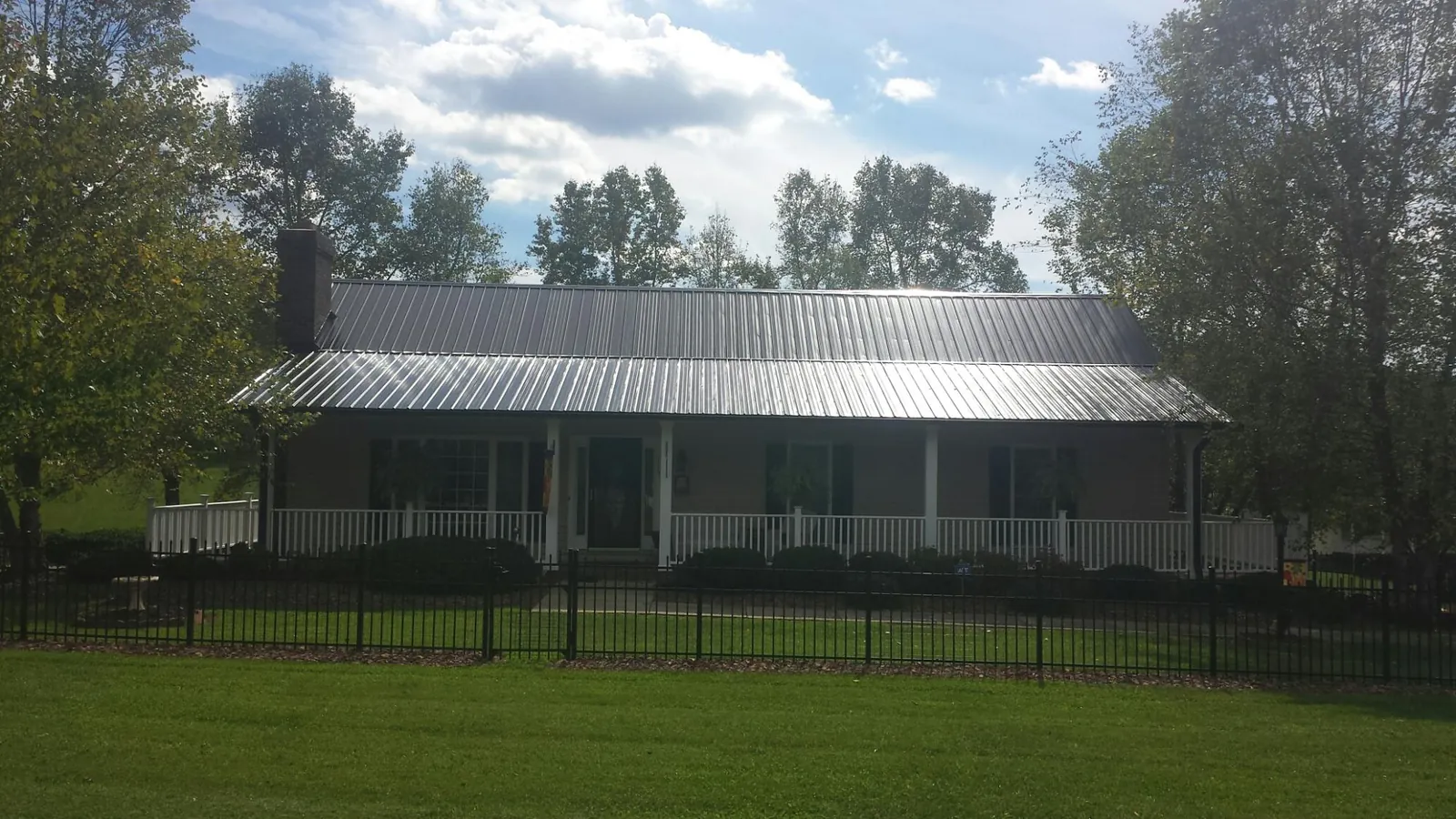Gray metal roof on a brick ranch with a full width front porch — Gutter Guard Installation work by our crew in Ashley Falls