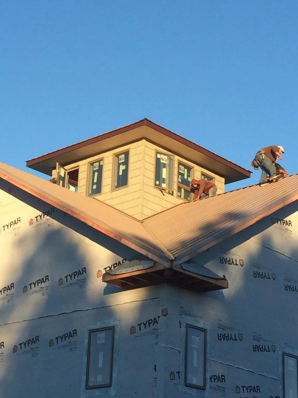 Roofers working around a rooftop cupola on a new metal roof at sunset — Roof Waterproofing in Ashley Falls by Roofing Brothers